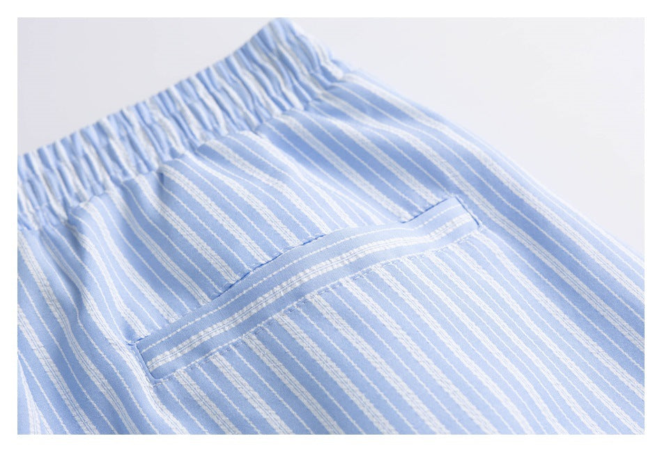 Close-up of a stitched pocket on light blue shorts with narrow white stripes.