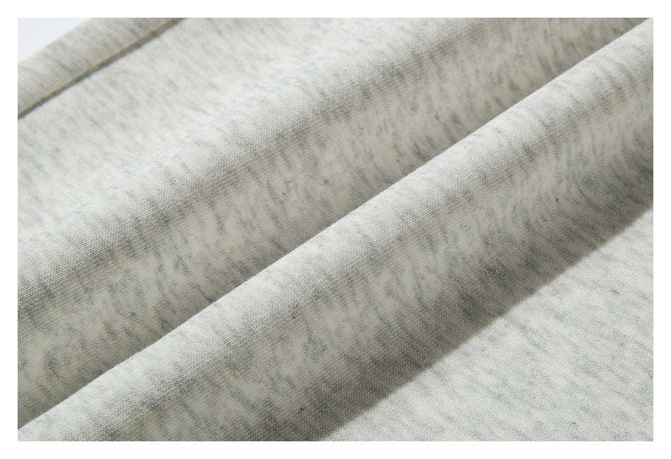 Close-up of light gray mottled fabric with a fine knit texture and soft folds.