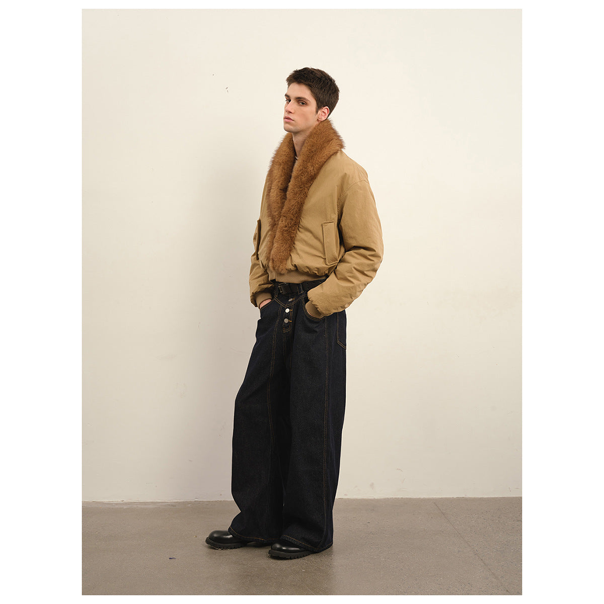 Model in a tan bomber jacket with a wide brown plush collar and black wide-leg jeans, shown at an angle.