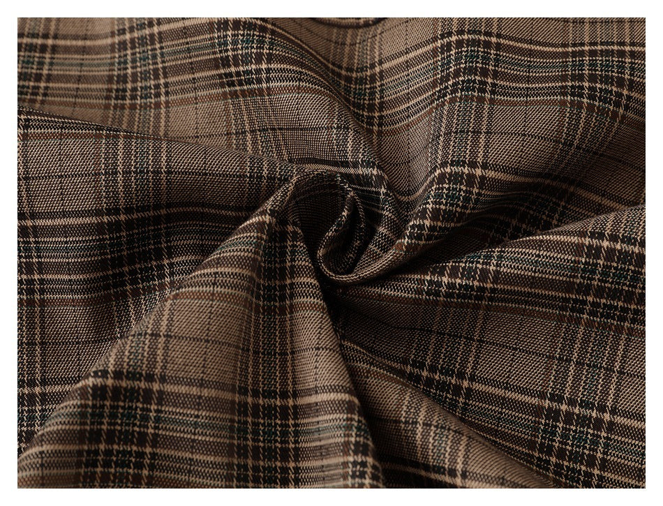 Close-up of brown, black, and muted green plaid fabric gathered into folds.
