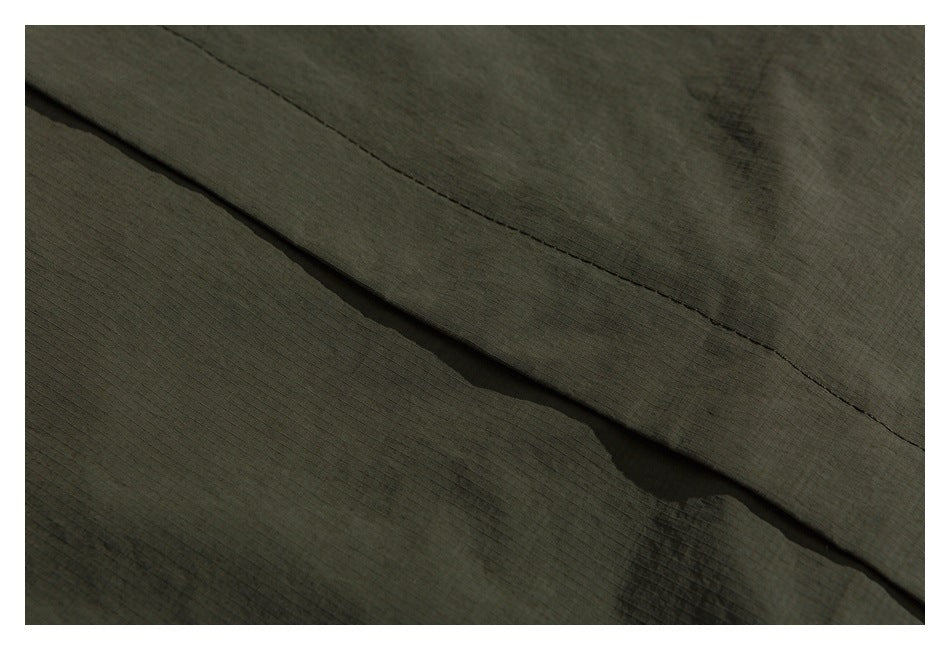 Close-up of an overlapping stitched seam on olive fabric.