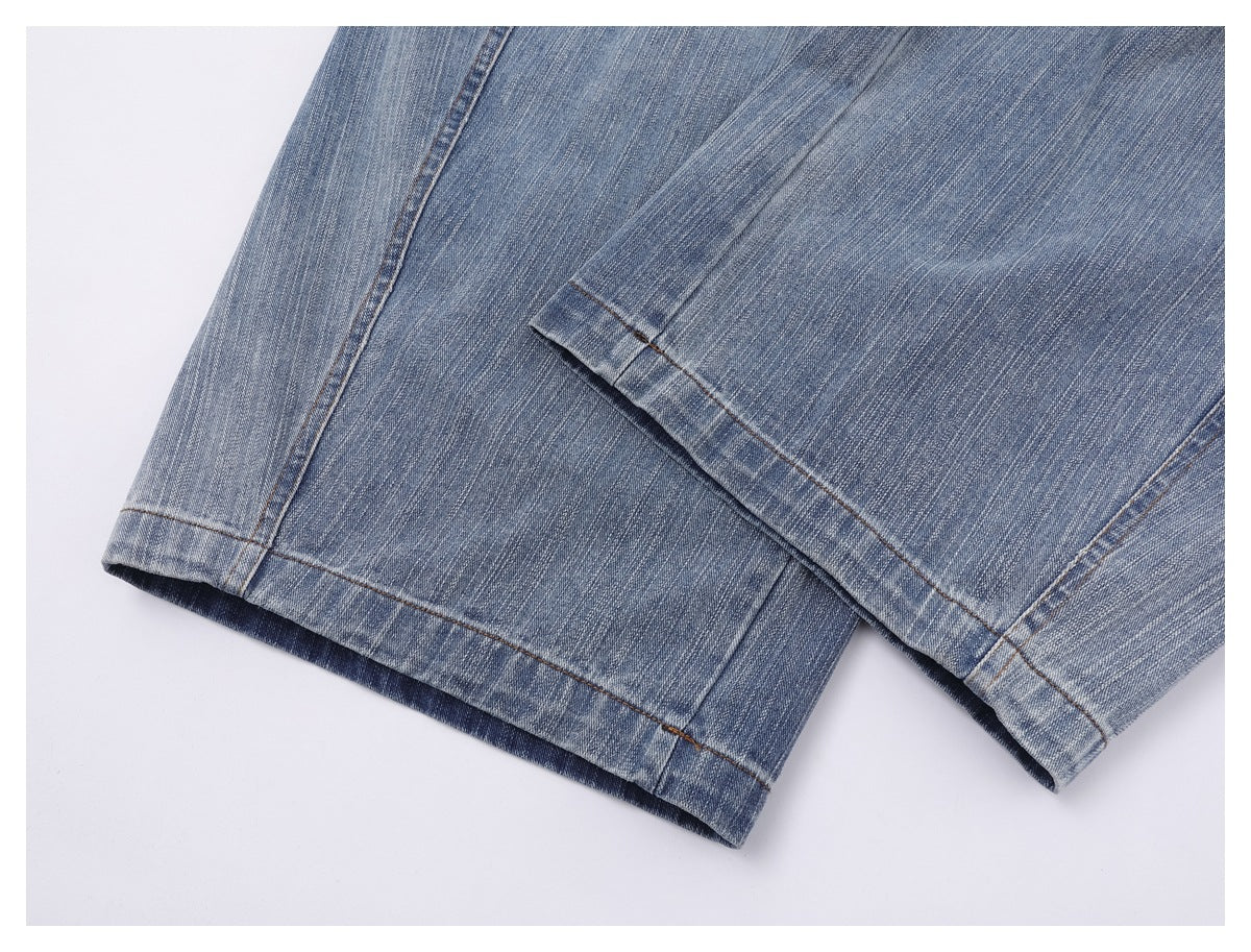 Close-up of the faded blue jeans' stitched leg hems.