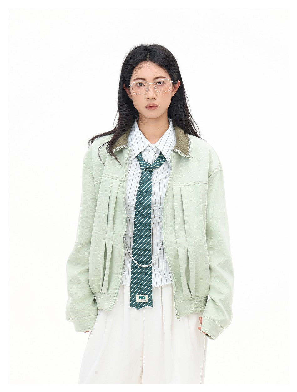 Front view of model in mint green pleated zip jacket with contrast collar, striped shirt, tie and white trousers