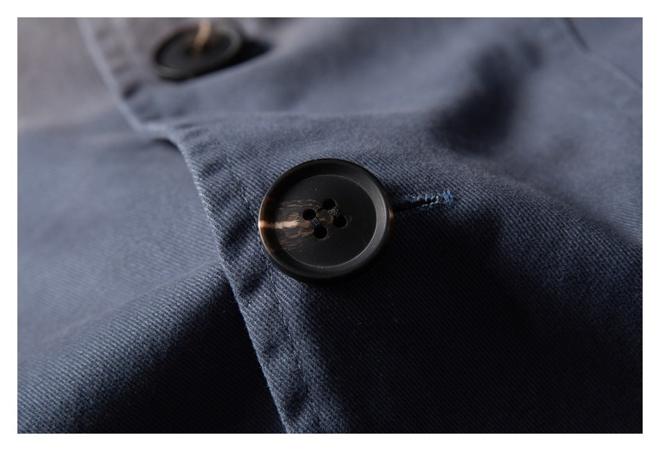 Macro view of a dark button and stitching on blue-gray jacket fabric.
