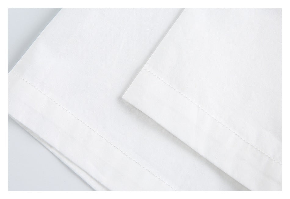Close-up of overlapping white garment hems with visible stitching.