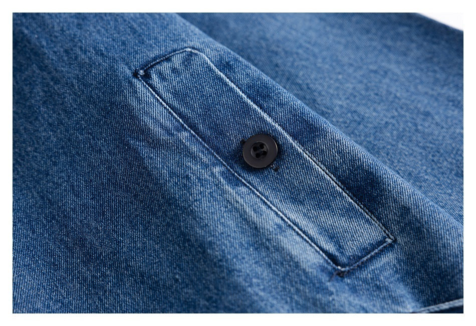 Close-up of a stitched button tab on blue denim fabric.