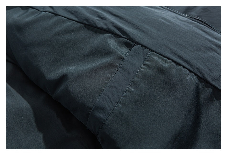 Close-up of dark charcoal garment fabric with stitched panel seams and part of a zipper.