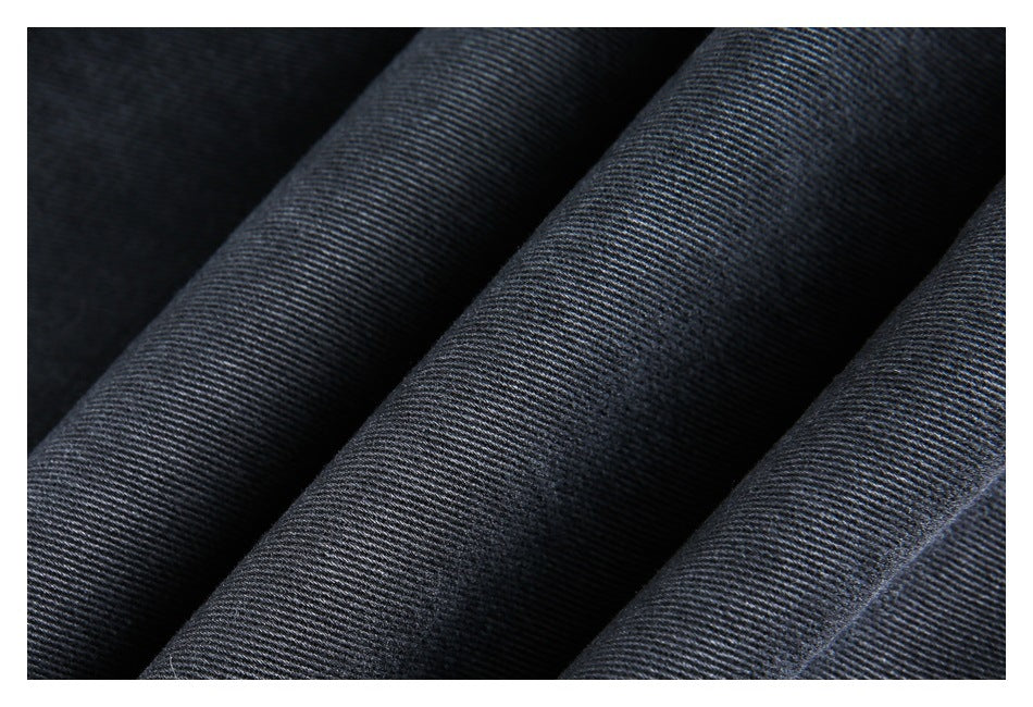 Macro view of the diagonal weave and folds of dark charcoal denim.