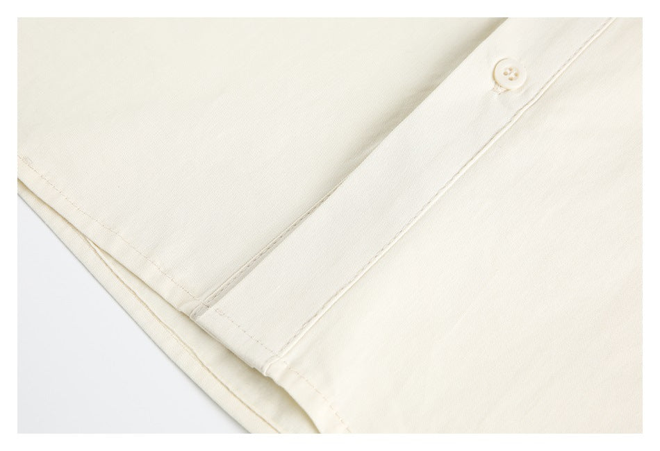 Close-up of the ivory shirt's button-front placket and stitched lower hem.