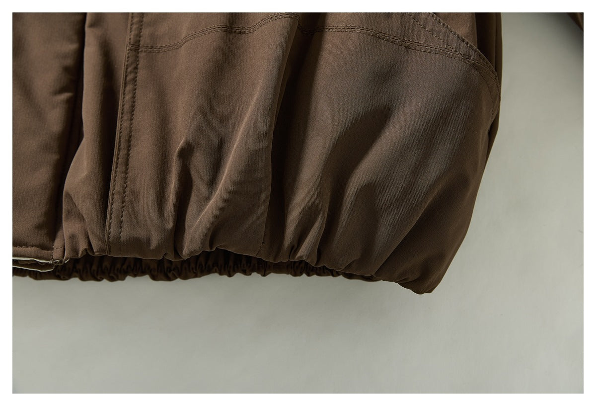Close-up of a brown jacket's lower pocket and gathered elastic hem.
