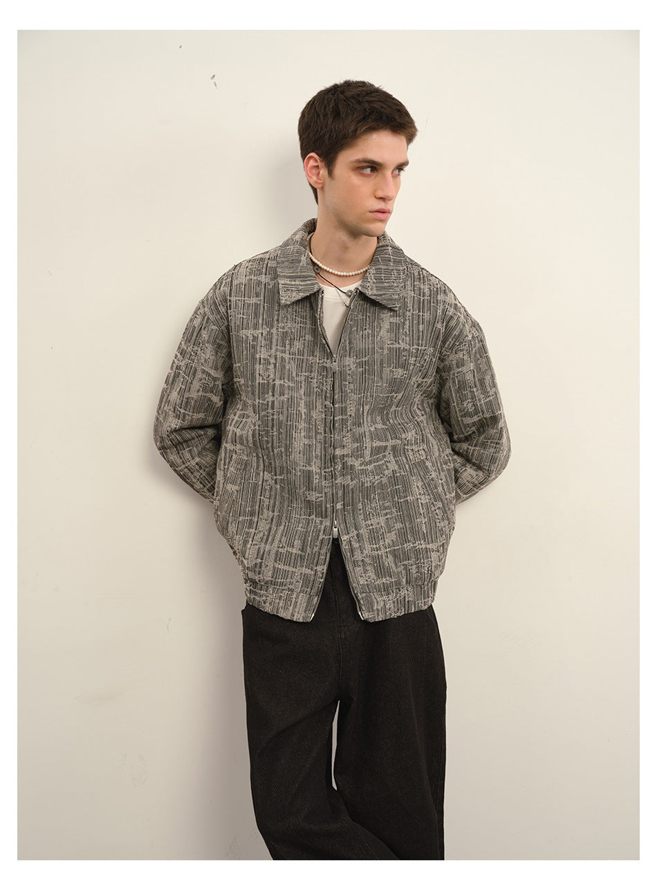 Model in a gray textured zip-front collared jacket with a white top and pearl necklace, hands behind back