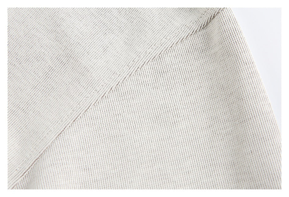 Close-up of ivory knit fabric showing a diagonal seam or panel join.