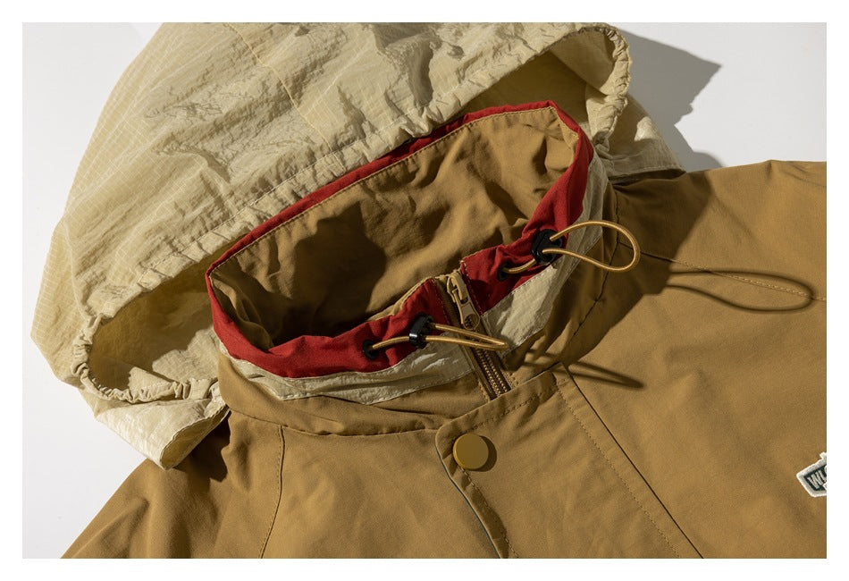 Close-up of a tan jacket’s hood, red collar trim, zipper, and drawcords.