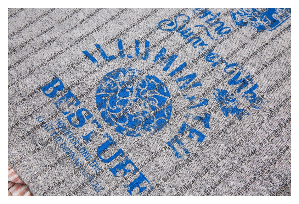Blue lettering and a circular graphic printed on the striped, distressed knit of a gray sweater.