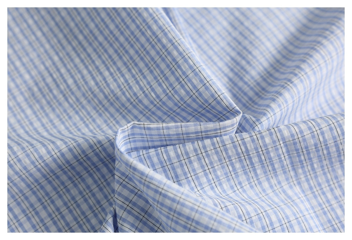 Close-up of draped light blue and white checkered fabric with fine dark grid lines.