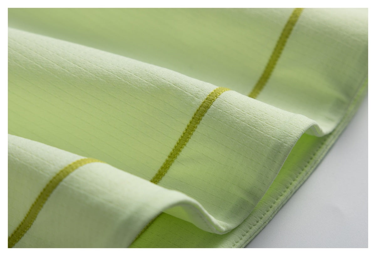 Close-up of pale lime fabric with a folded hem and contrasting yellow-green stitching.