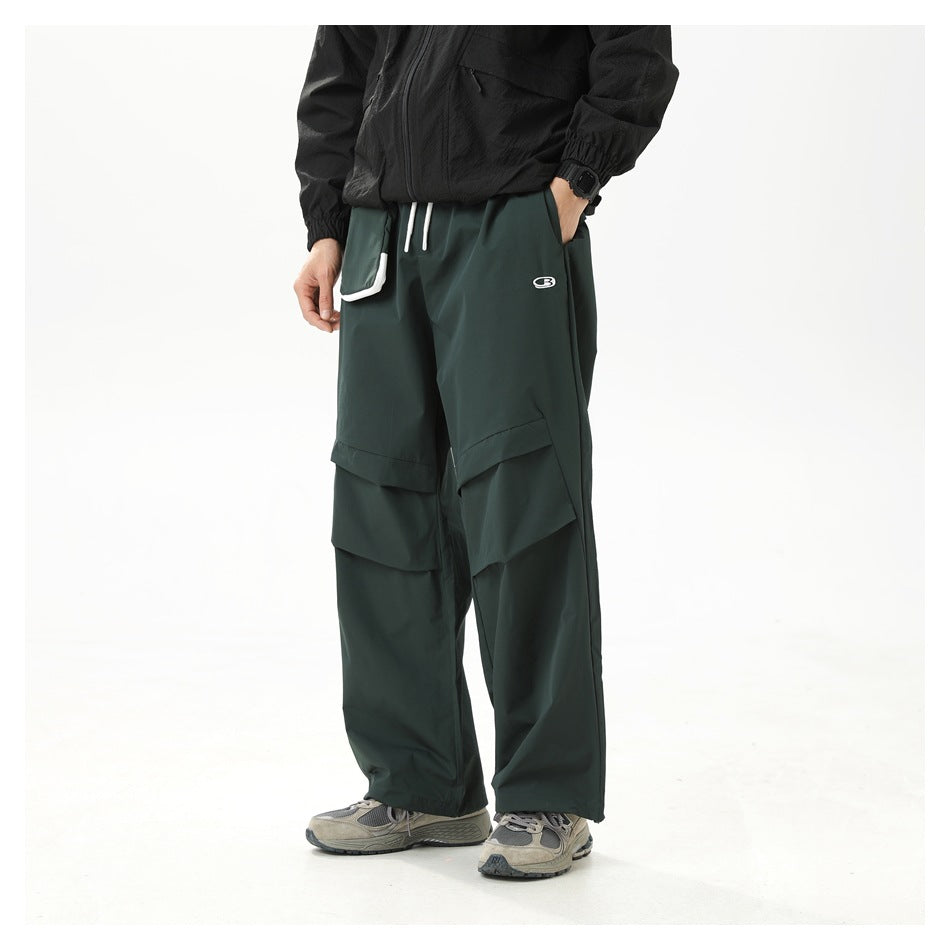 Model wearing loose dark green cargo pants with layered thigh pockets and a white-trimmed waist pocket.