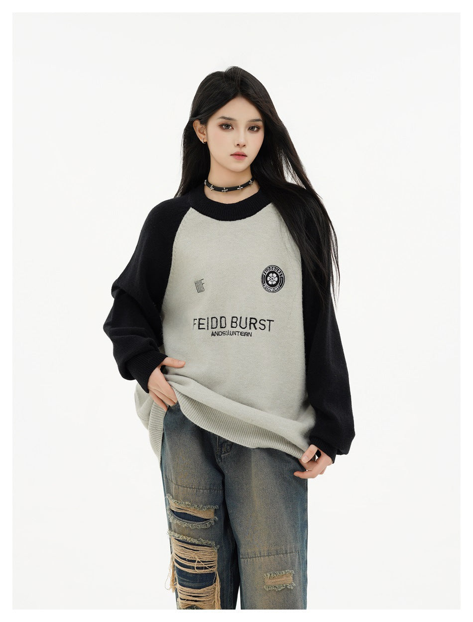 Model wearing a gray and black raglan crewneck sweater with ripped wide-leg jeans, hands lowered at the hem