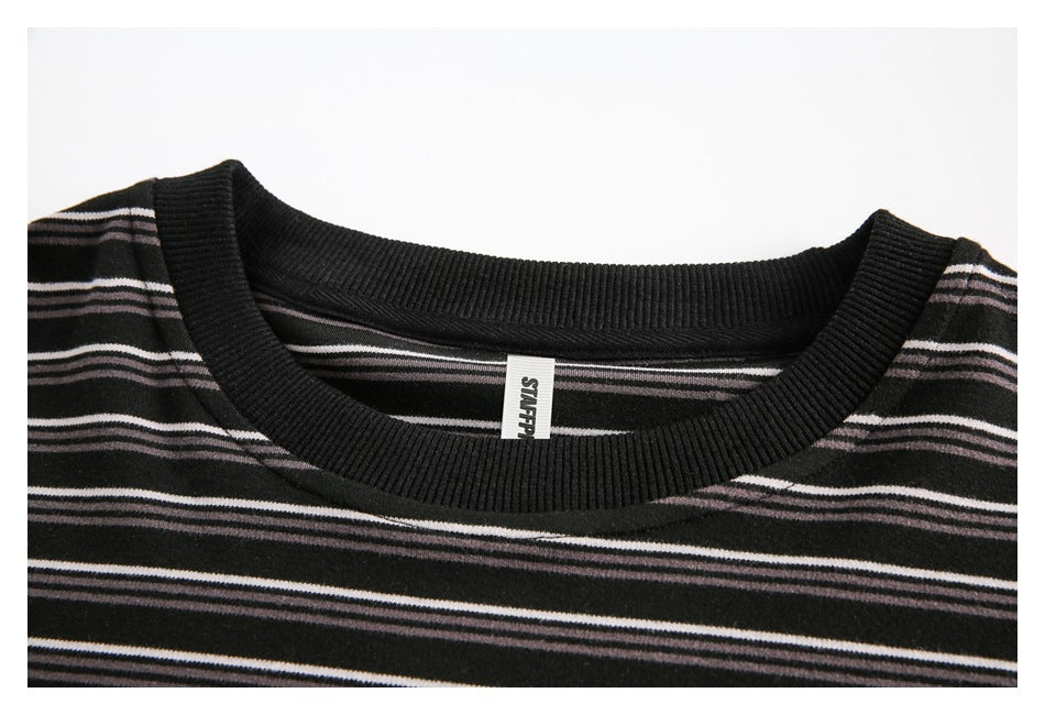 Close-up of a black ribbed crew neckline on a striped top, with a small white neck label.