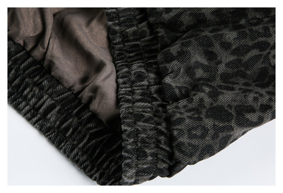 Close-up of dark charcoal leopard-print garment with a gathered edge and glimpse of brown lining.