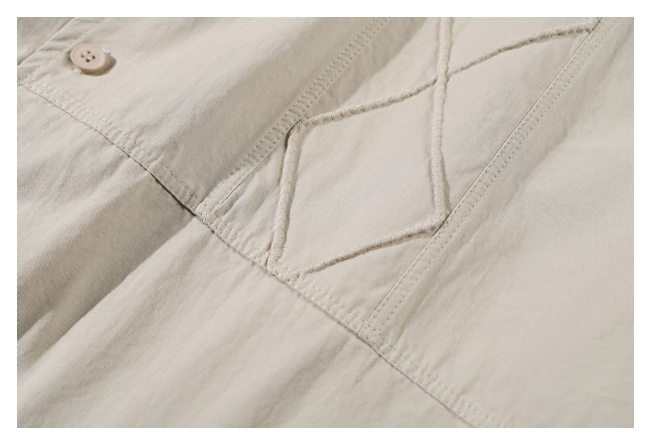 Close-up of beige garment stitching and a curved seam with a small matching button.