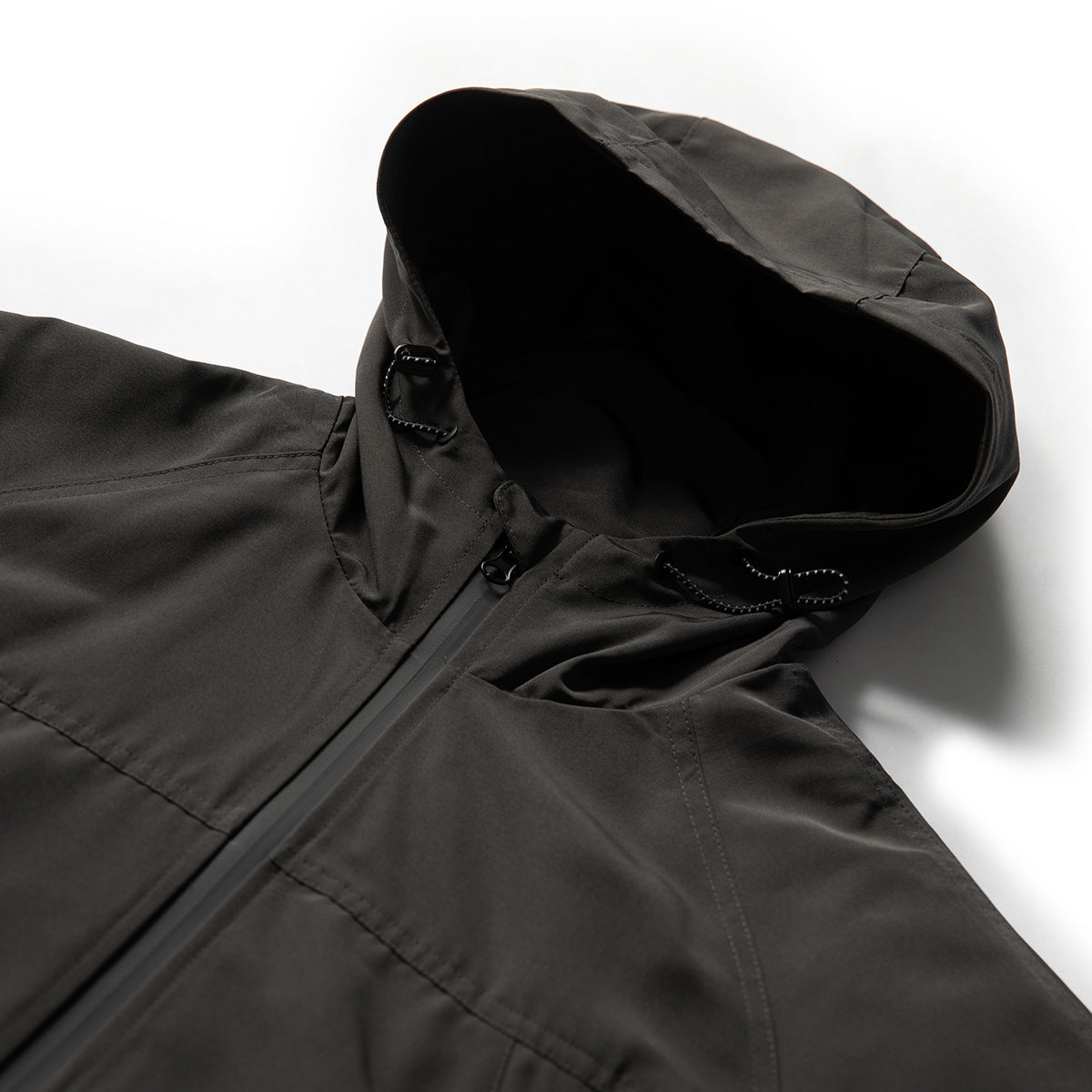 Close-up of a charcoal hooded jacket showing the hood, drawcords and front zipper.