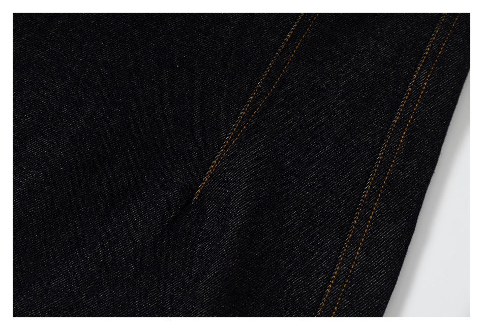 Close-up of black denim pants showing parallel orange-brown stitched seams.