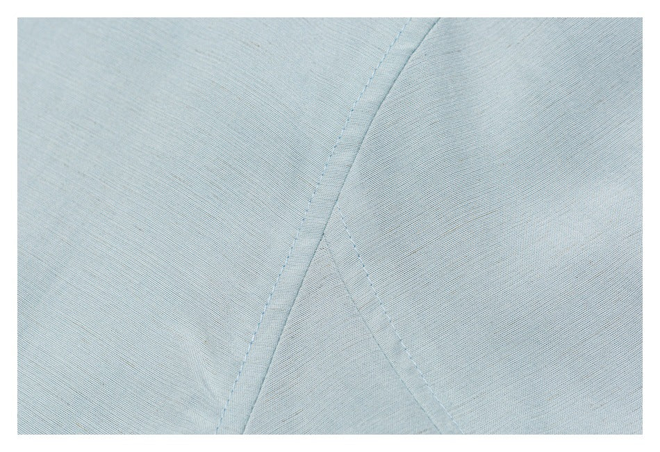 Close-up of intersecting stitched seams on pale blue fabric.