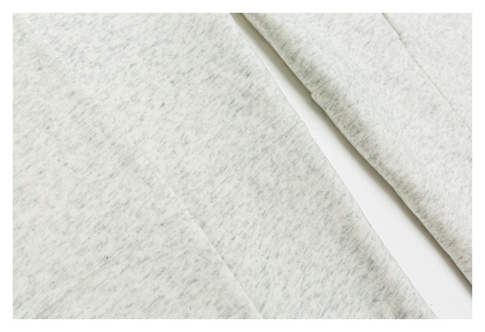 Close-up of light gray mottled garment panels and seam stitching.