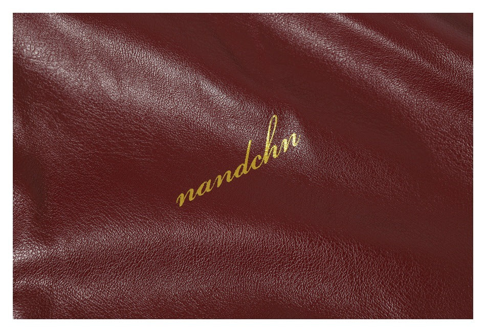 Close-up of gold cursive embroidery on the textured burgundy jacket material.
