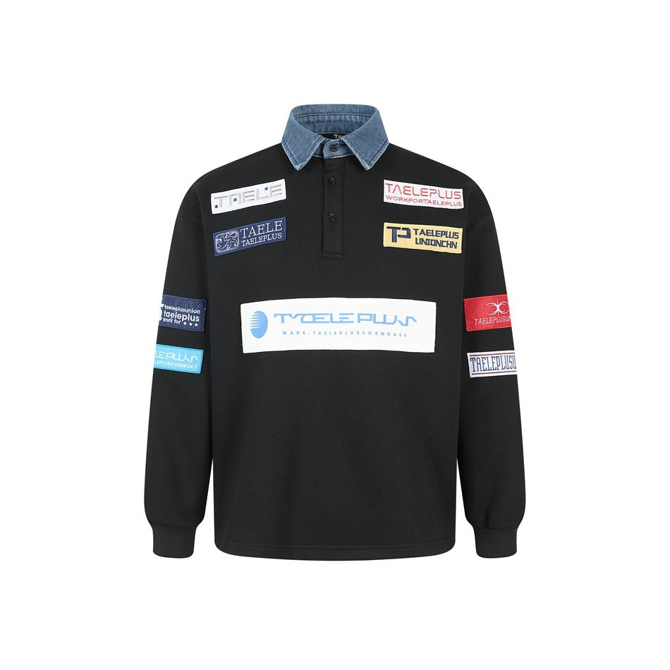 Front view of a black long-sleeve pullover with a blue denim collar, ribbed cuffs and colorful sewn patches.