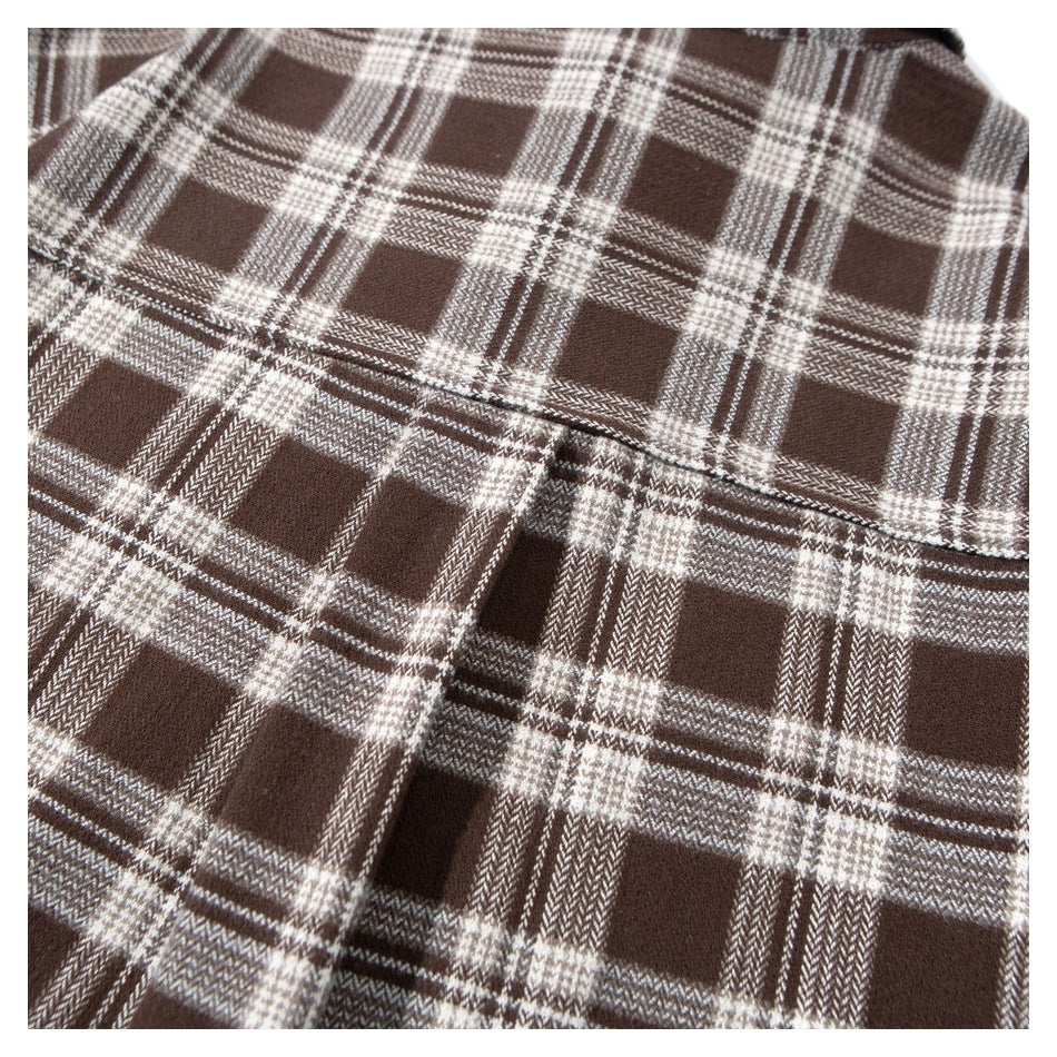Close-up of a brown and cream plaid shirt showing a curved pocket seam.