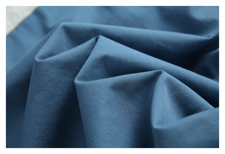 Close-up of blue shirt fabric arranged in soft folds, showing its surface and texture.