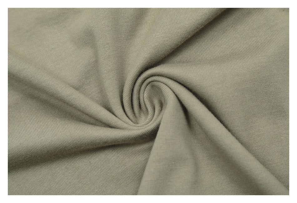 Close-up of muted khaki fabric gathered into a spiral, showing its knit texture.