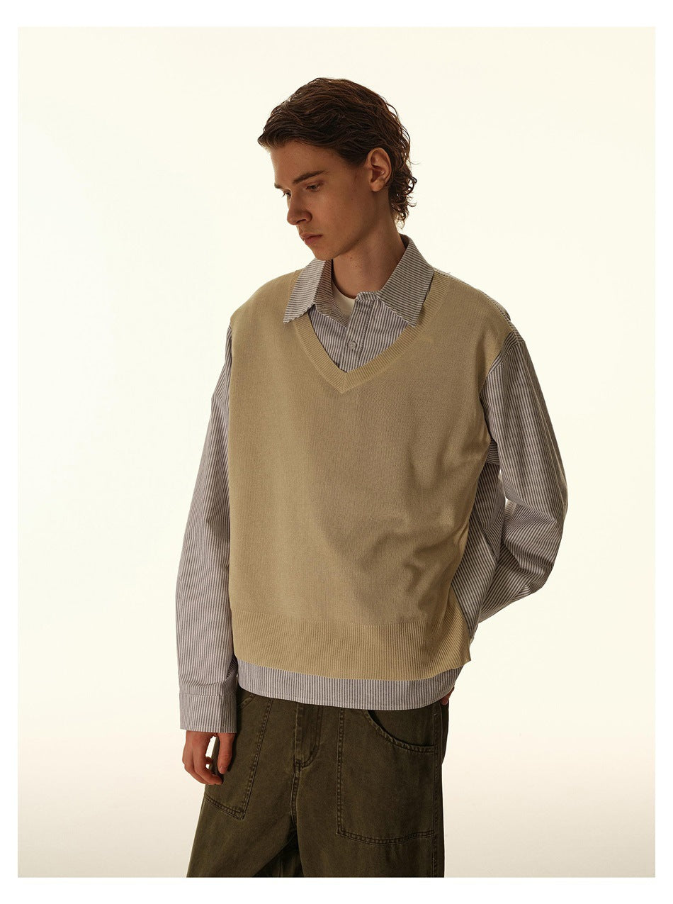Closer view of a male model wearing a beige V-neck vest over a fine-striped button-up shirt.