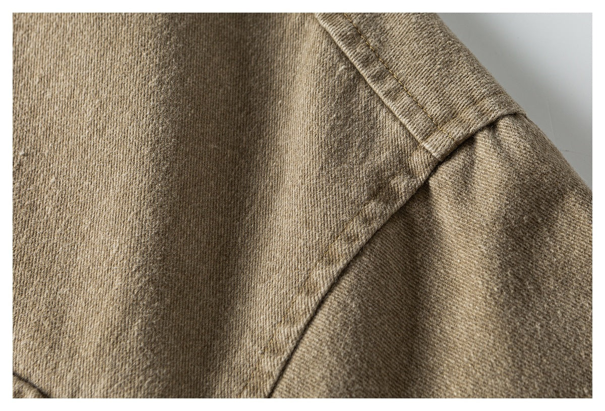 Close-up of tan jacket fabric with a stitched shoulder seam and sleeve seam.