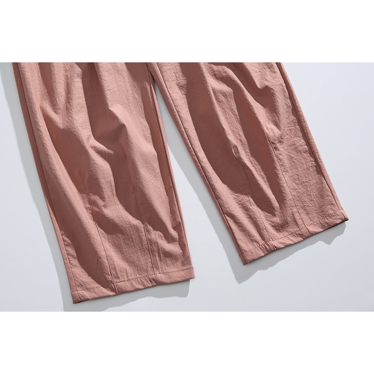 Close-up of the dusty rose pants' wide legs and stitched hems.