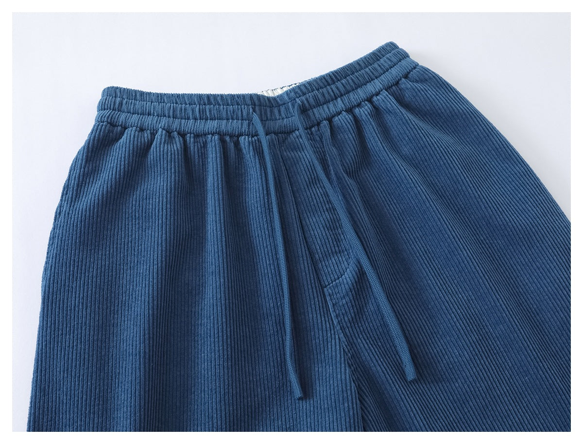 Close view of blue ribbed corduroy pants showing the elastic waistband, drawstring, and front pocket.