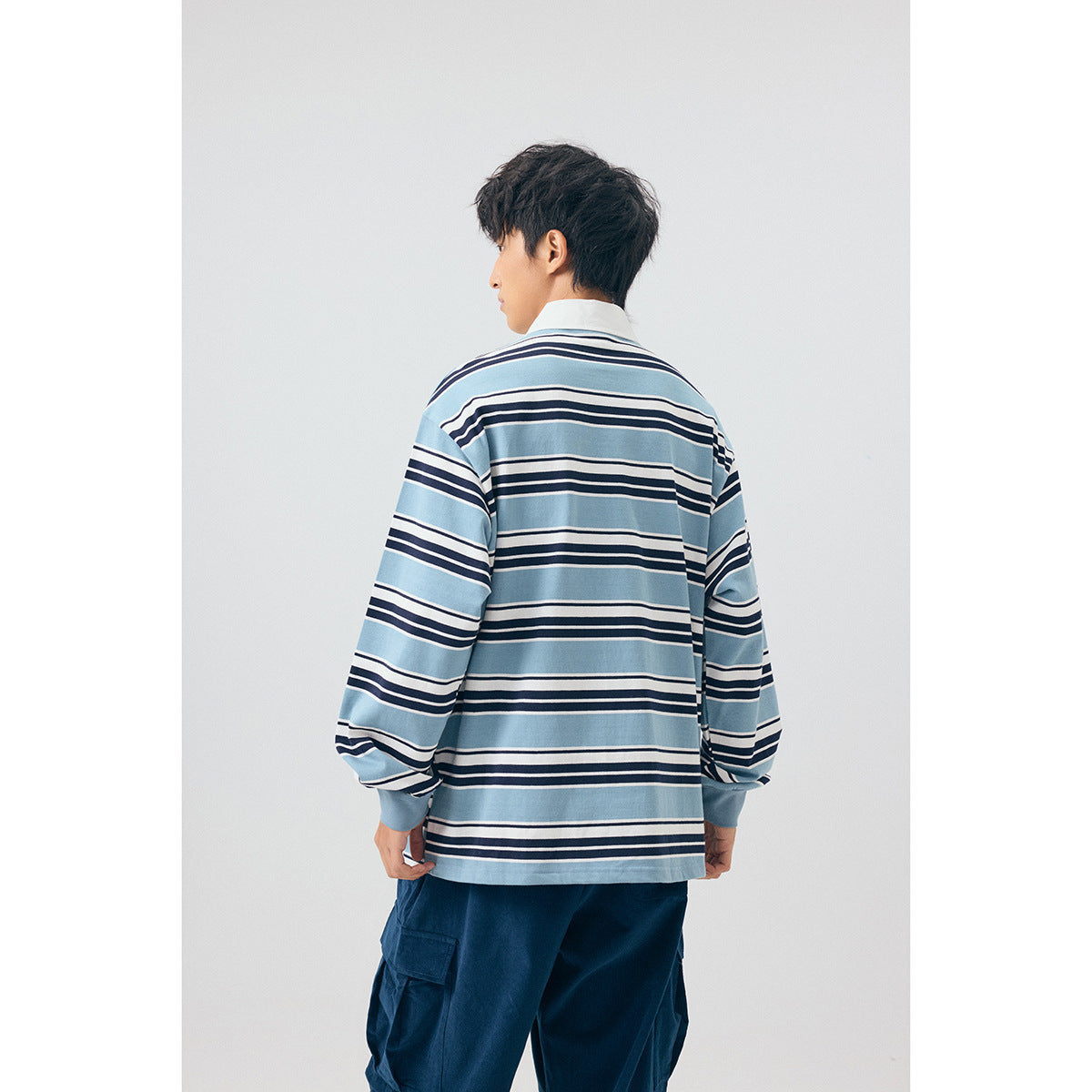 Back view of a model wearing a blue, white, and navy striped long-sleeve collared shirt.