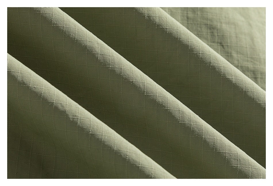Macro view of olive-green fabric showing its fine grid-like weave and folds.