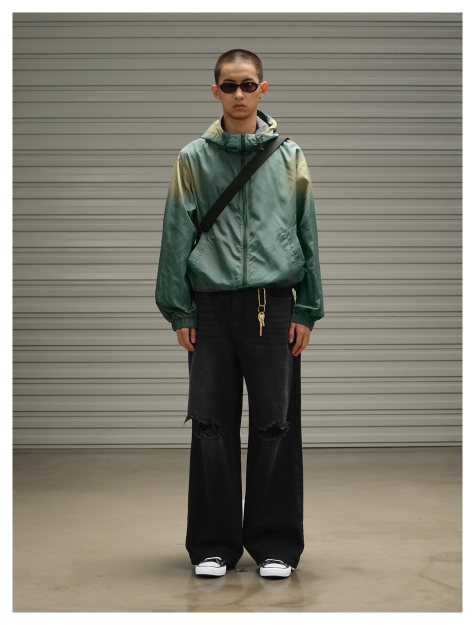 Full-length front view of a model wearing a green hooded zip jacket and wide black distressed jeans.