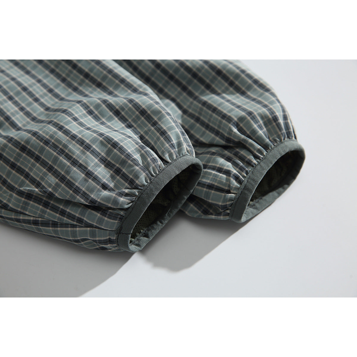 Close-up of the gray-green plaid jacket's gathered sleeve cuffs with dark trim.