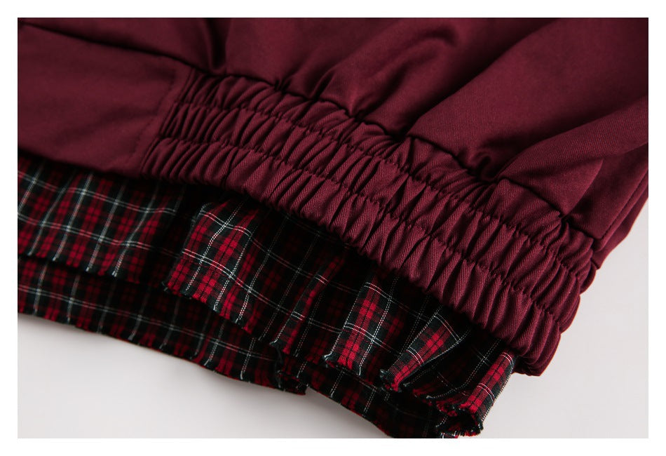 Close-up of the jacket's gathered burgundy hem with plaid lining beneath.