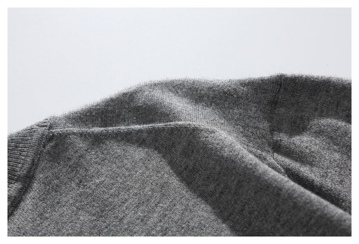 Close-up of gray knit sweater fabric and a seam, arranged in soft folds.