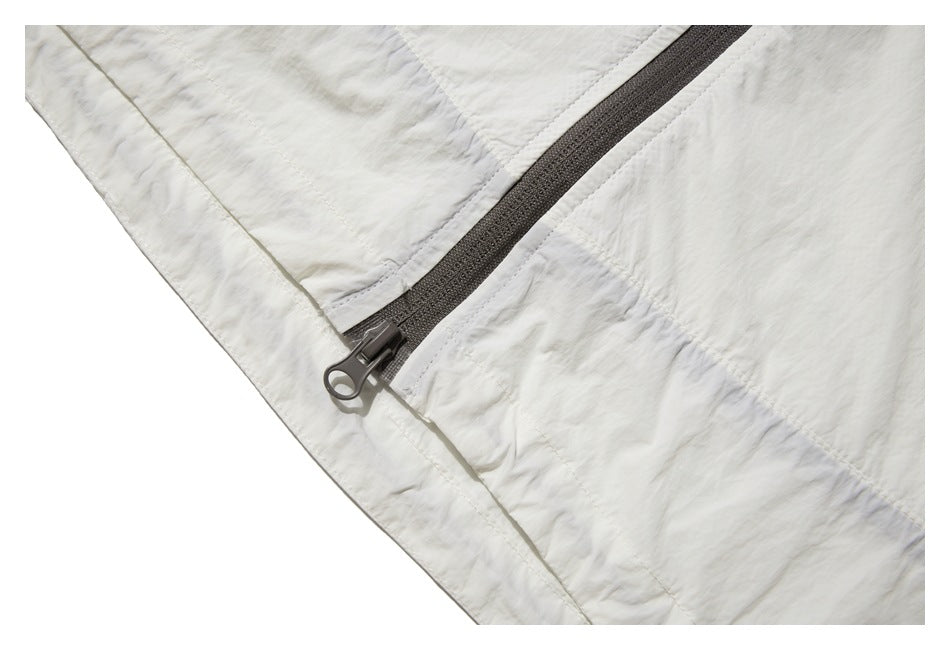 Close-up of a dark zipper with a ring-shaped pull on off-white fabric.