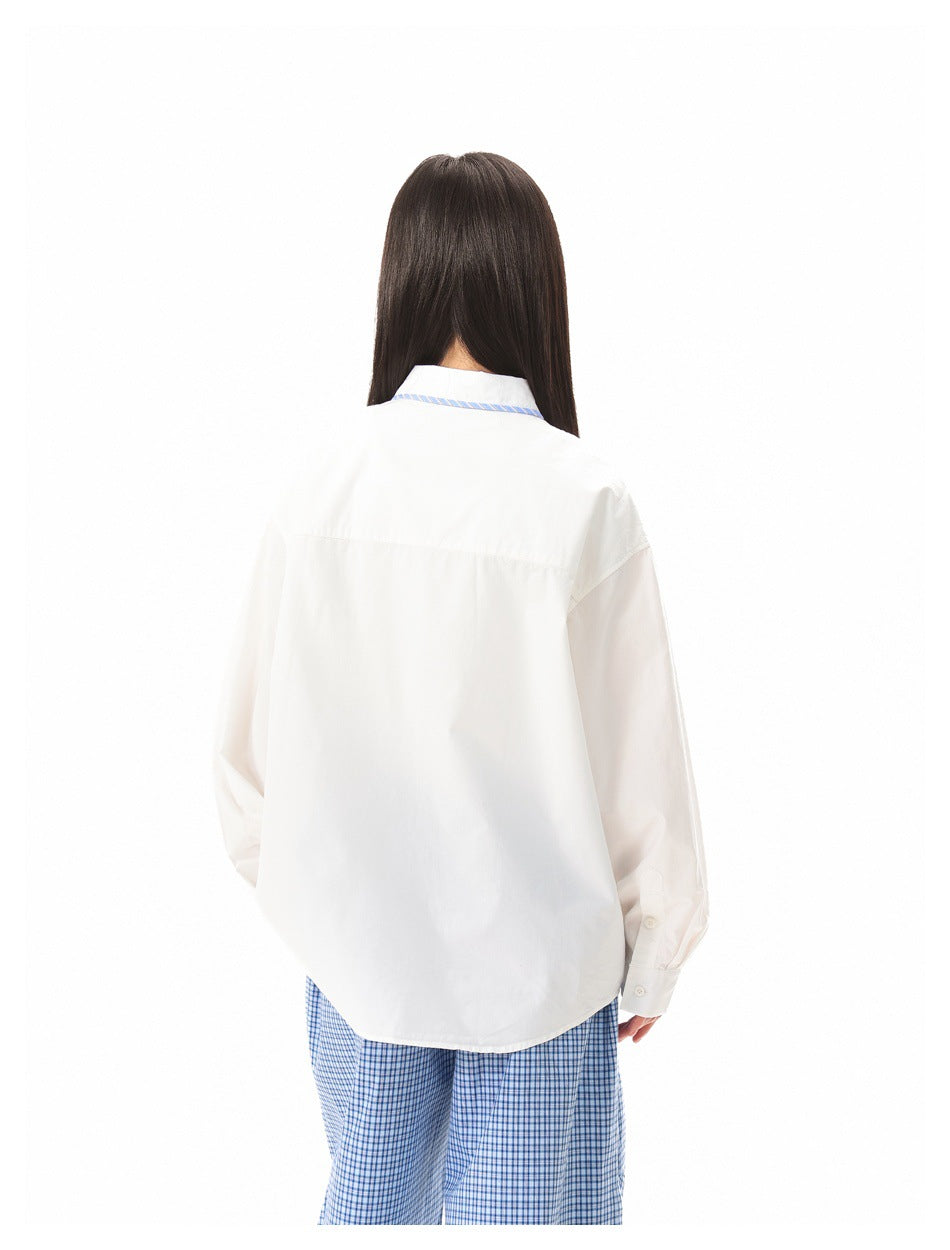 Closer back view of a model wearing a white shirt with blue striped collar and blue checked trousers.