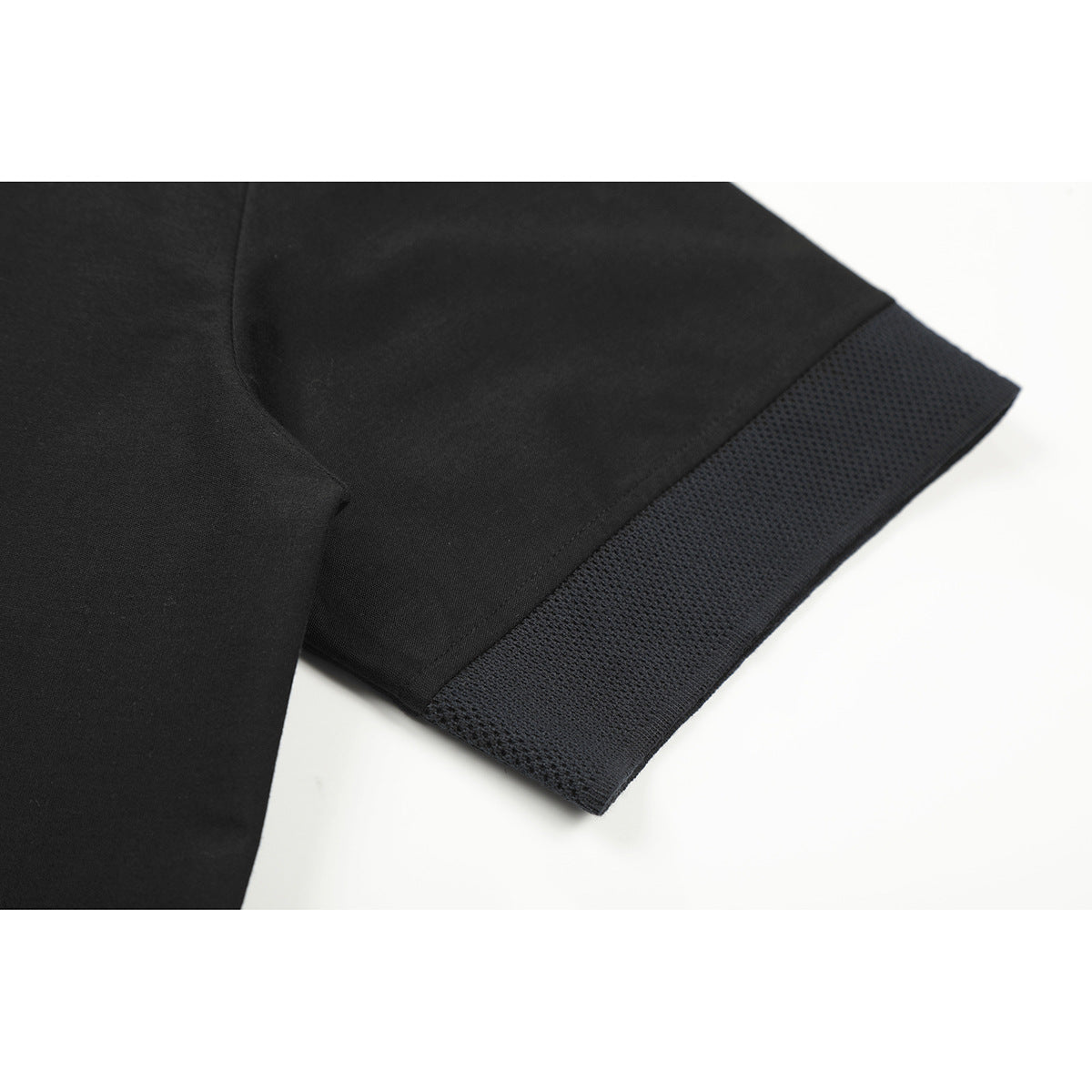Close-up of a black T-shirt sleeve with a wide dark textured trim at the hem.