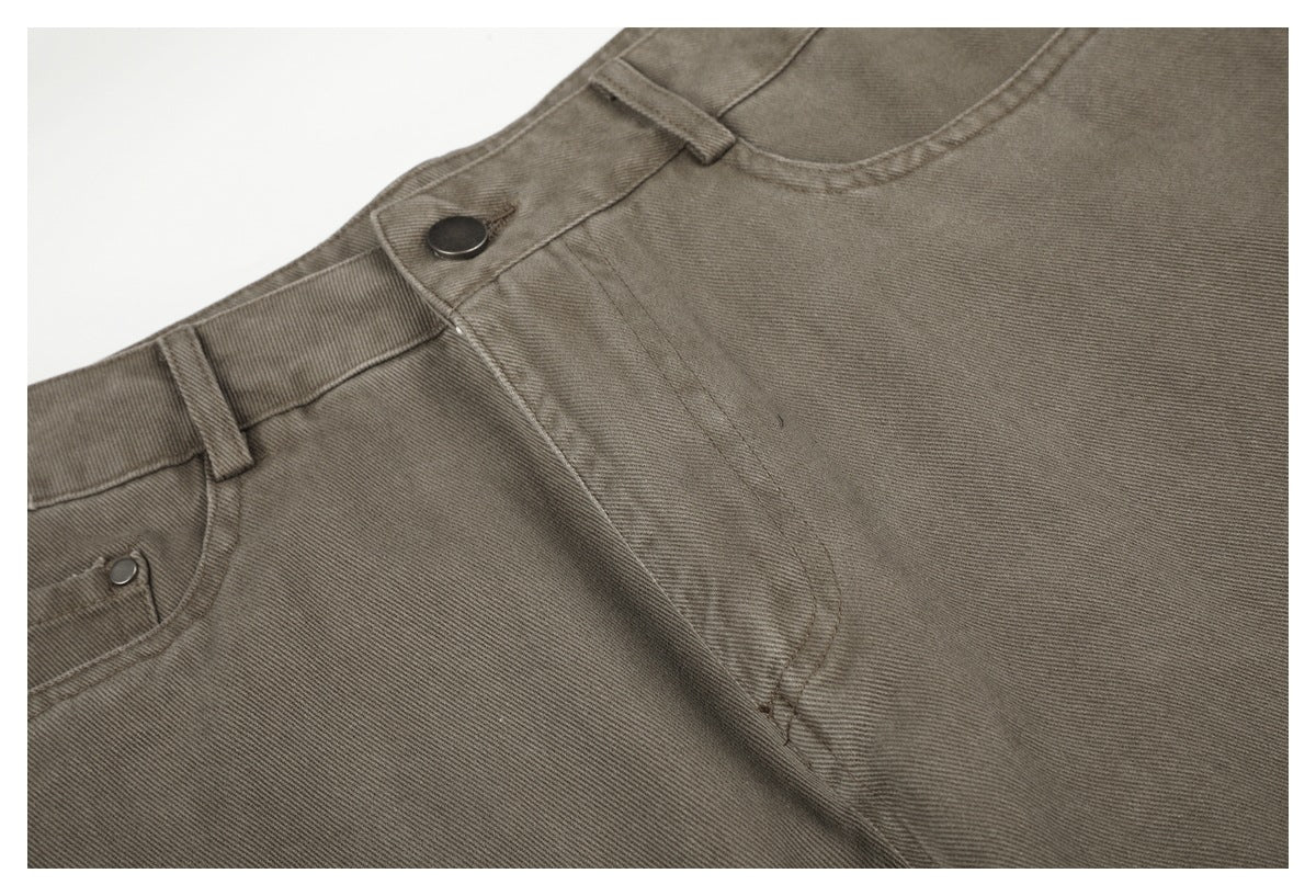 Close-up of taupe-gray pants showing the front button, fly seam, waistband, and pocket edge.