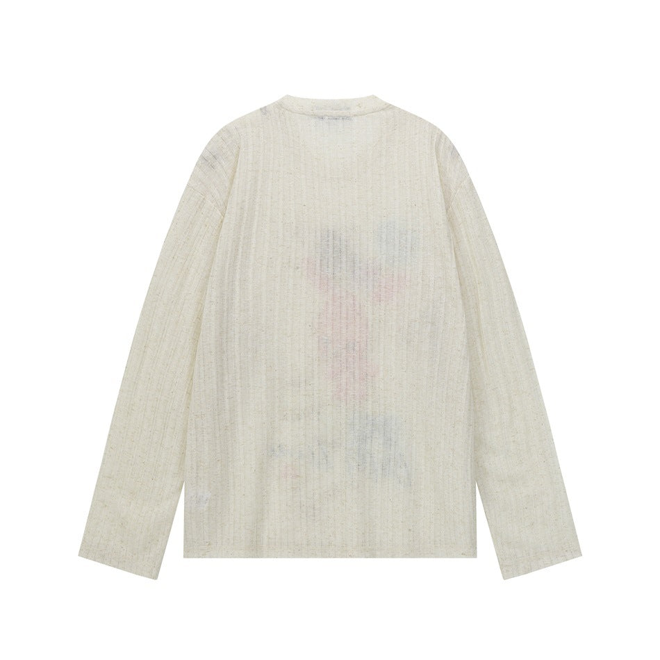 Back of cream ribbed long-sleeve top with faint pastel print showing through the sheer fabric