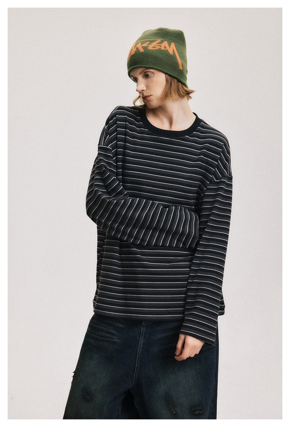 Closer view of a model wearing an oversized black shirt with fine gray stripes and a ribbed crew neck.